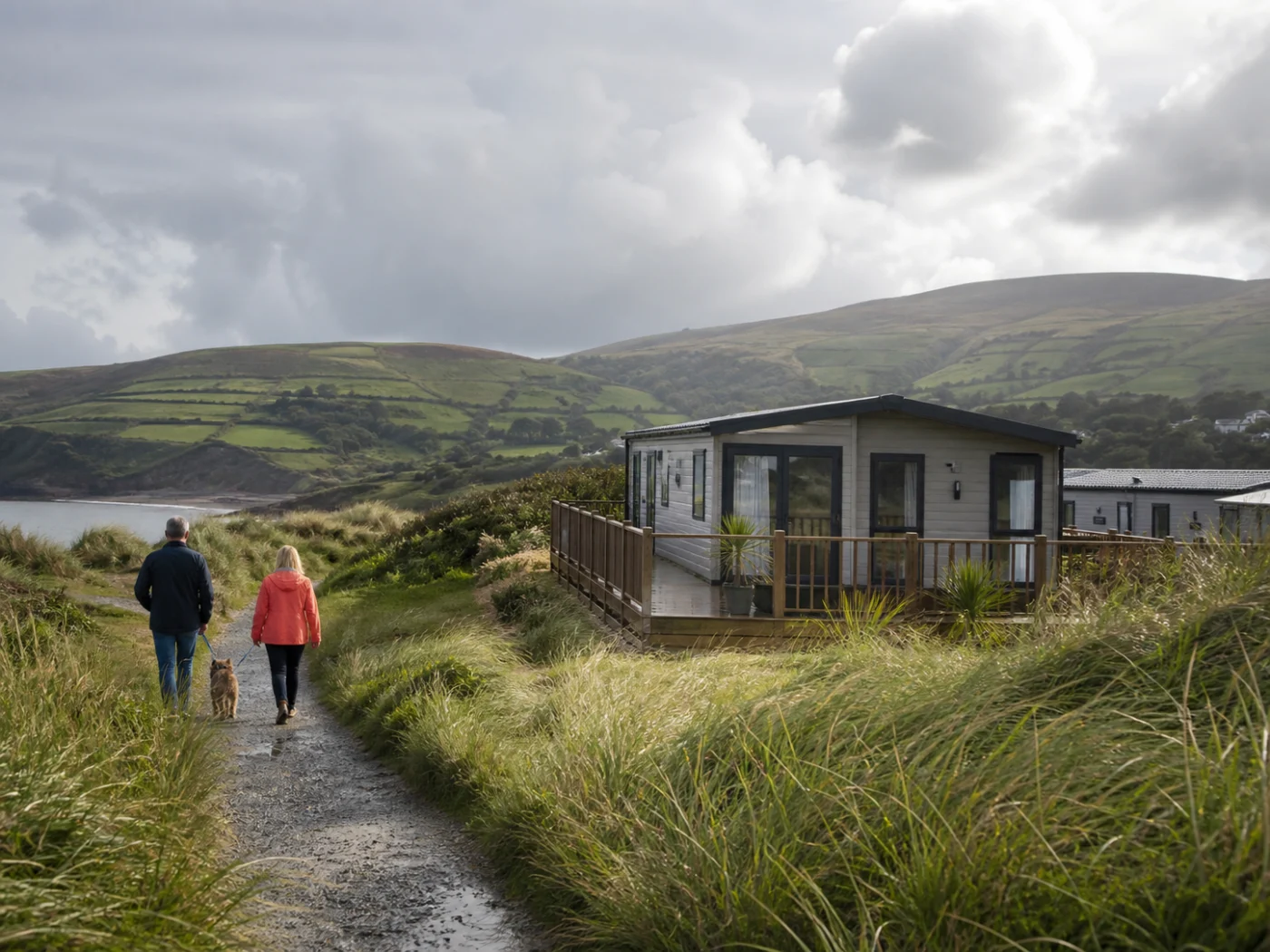 A couple walk through dunes beside a static holiday home on the North Wales coast