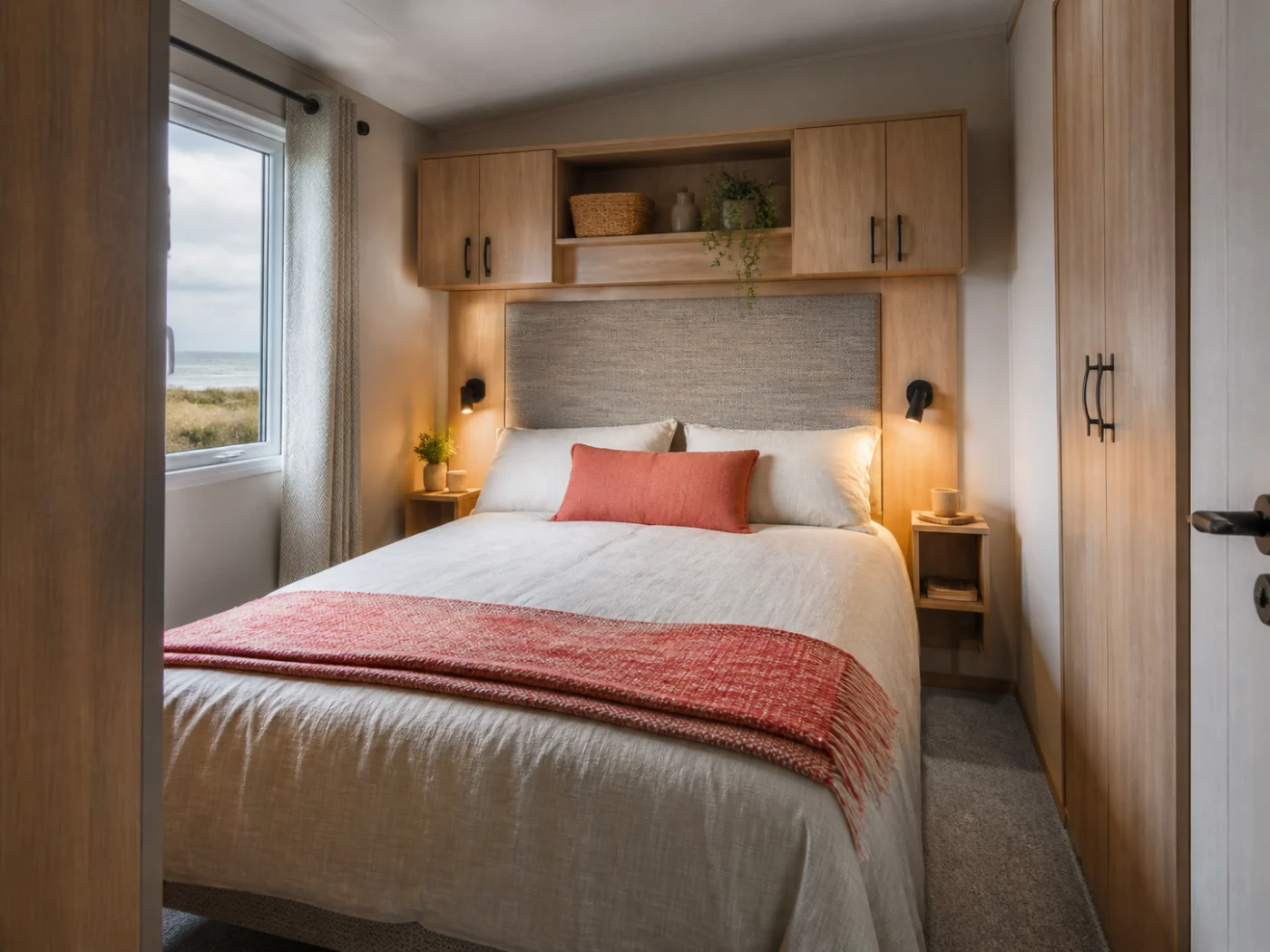 Main bedroom with pale oak storage and coral textiles